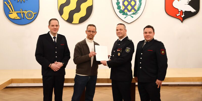 Vier Männer bei Urkundenübergabe