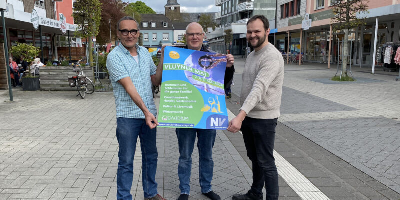 Drei Männer halten ein Plakat