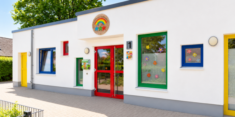 Weißes Flachdachgebäude mit bunten Fensterrahmen