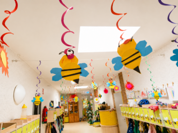 Aus Pappe gebastelte Bienen hängen an einer Flurdecke in einem Kindergarten