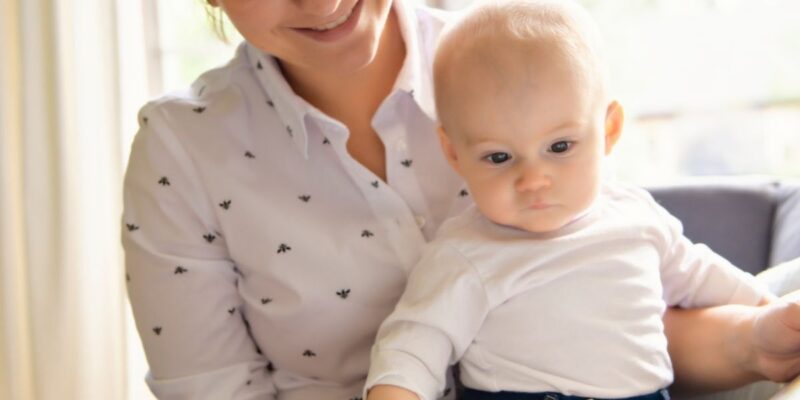 Eine Frau hat ein Baby auf dem Arm. Beide schauen gemeinsam in ein Bilderbuch.